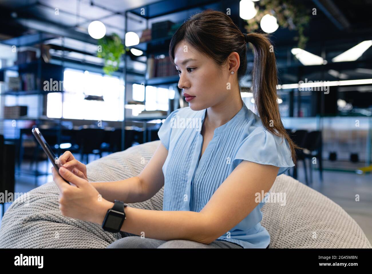 Asian woman sitting in a bean bag and holding a digital tablet Stock ...