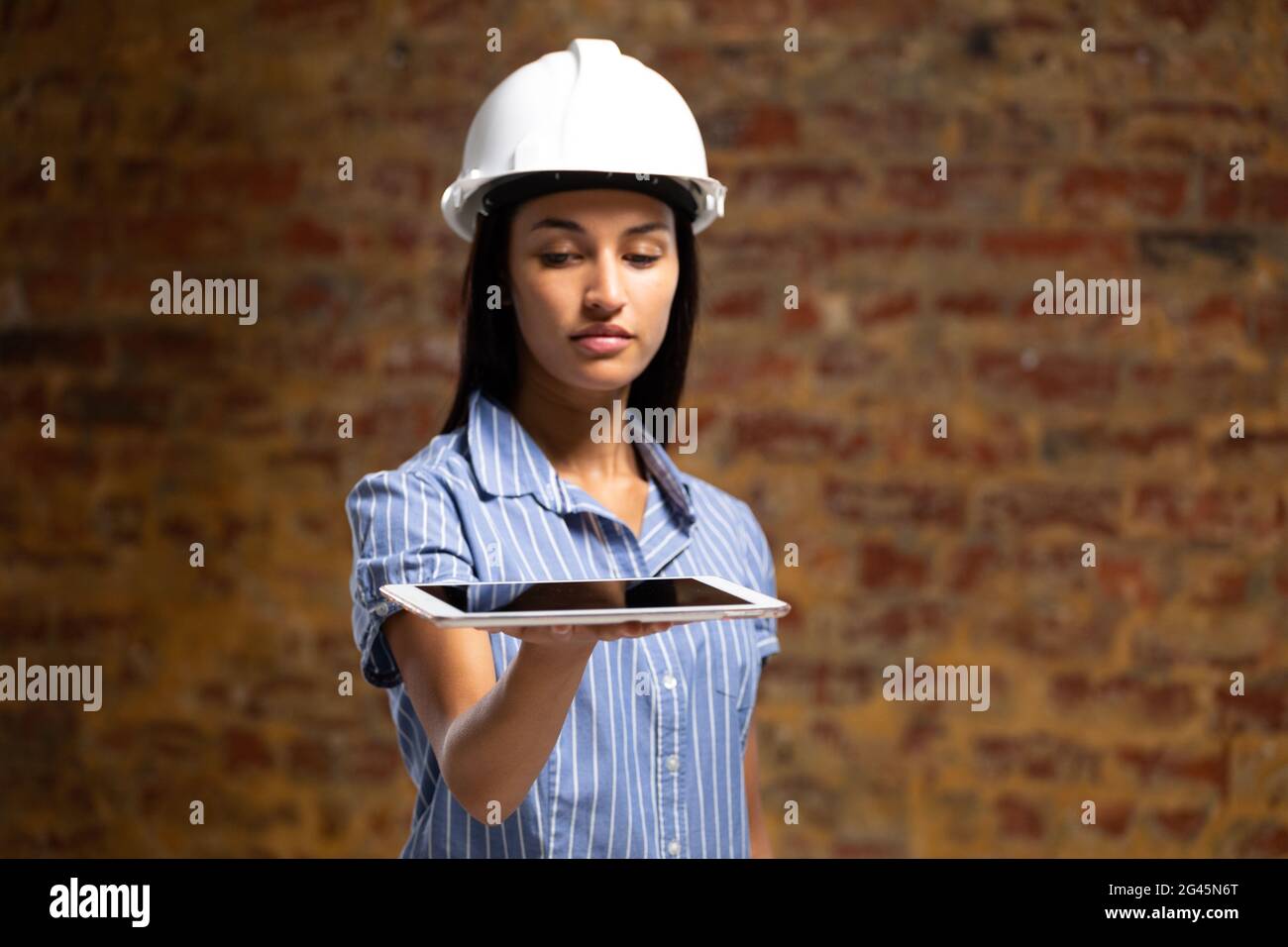 Mixed race female architect engineer holding a digital tablet Stock Photo