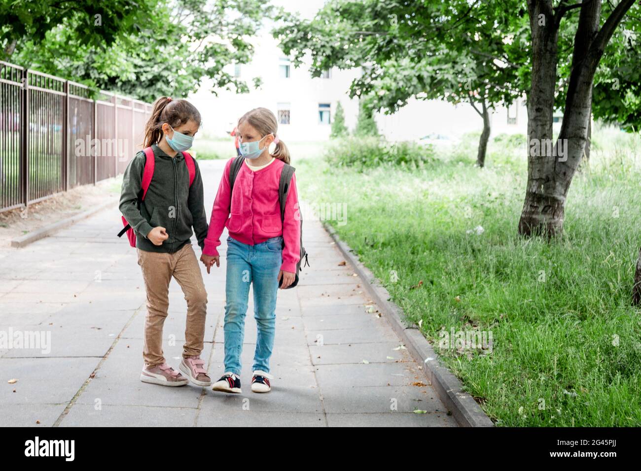 Two little schoolgirls going back to school during covid-19 pandemic ...