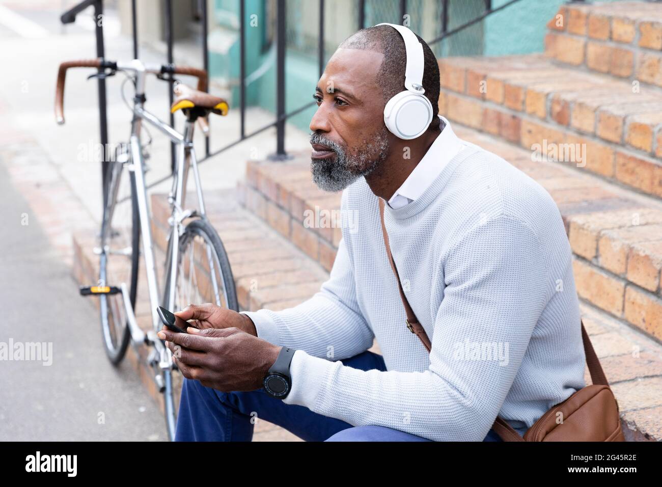 African American man sitting on stairs and listening music Stock Photo ...