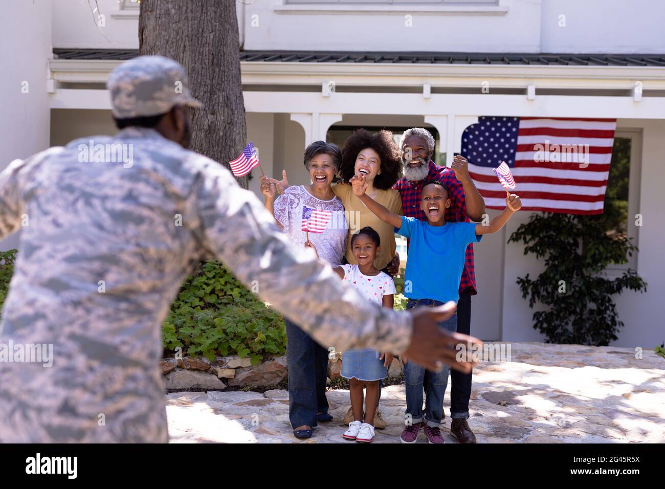 Multi-generation mixed race family welcoming an African American man wearing military uniform Stock Photo