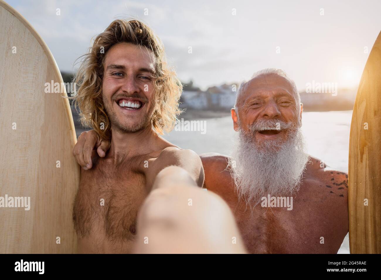 Happy fit surfers taking selfie while having fun surfing together at sunset time - Extreme sport lifestyle and friendship concept Stock Photo