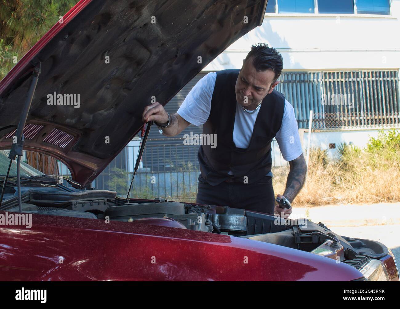 mature man fixing a breakdown in his car engine with tools on the side of the road Stock Photo