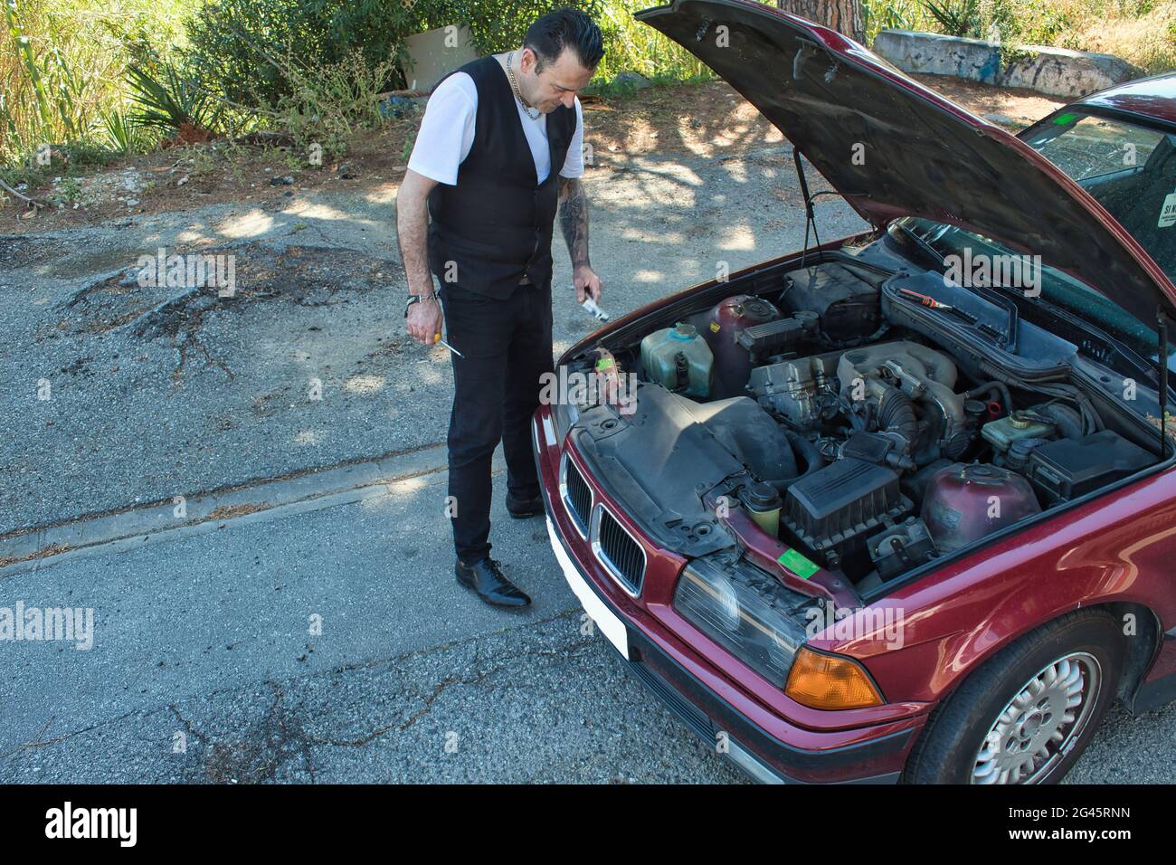 mature man repair a breakdown in his car engine with tools on the road Stock Photo