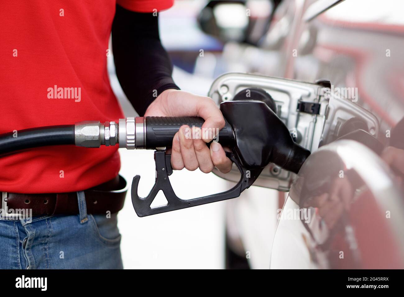 Gas station worker in red uniform filling up bronze pickup truck tank