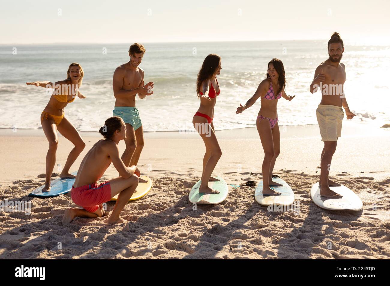 Multi-ethnic group of male and female, surfing on the beach Stock Photo