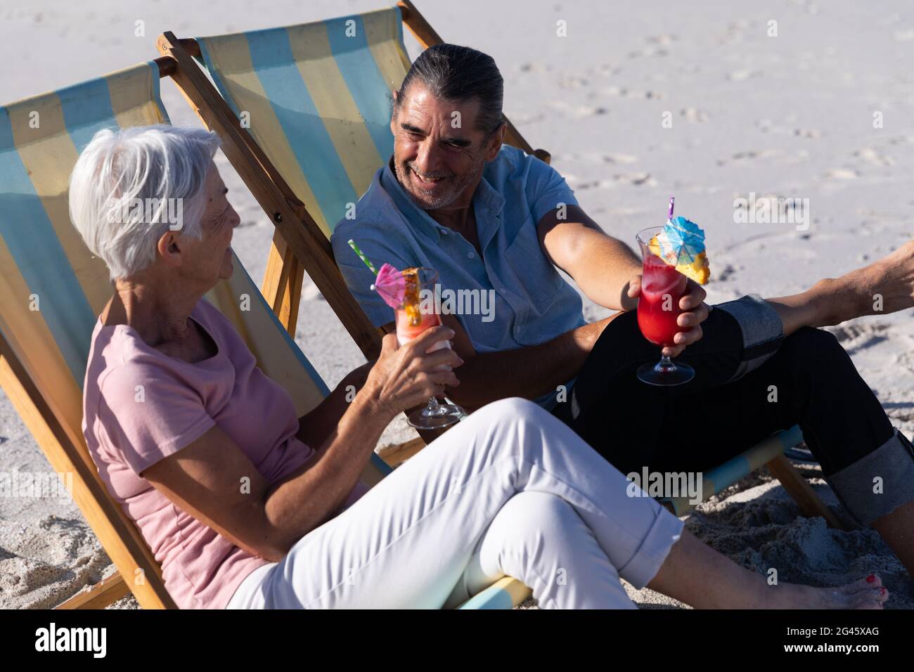 Senior Caucasian couple sitting on deck chairs at the beach Stock Photo ...