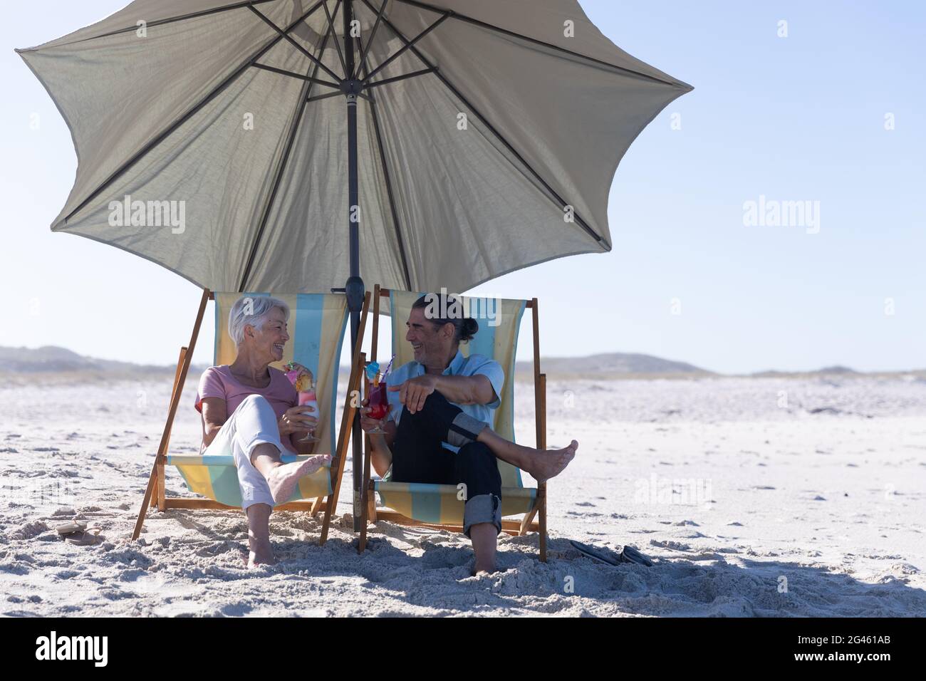 Senior Caucasian couple sitting on deck chairs at the beach Stock Photo ...