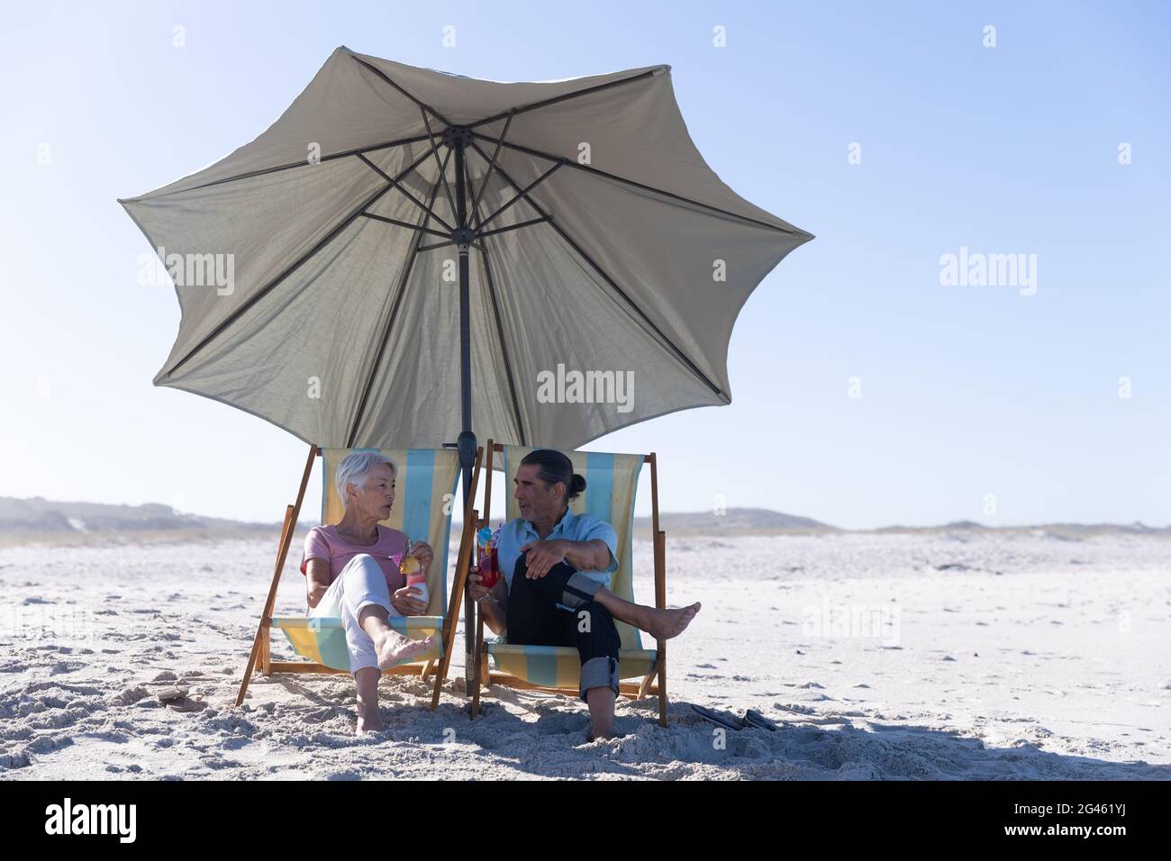 Senior Caucasian couple sitting on deck chairs at the beach Stock Photo ...
