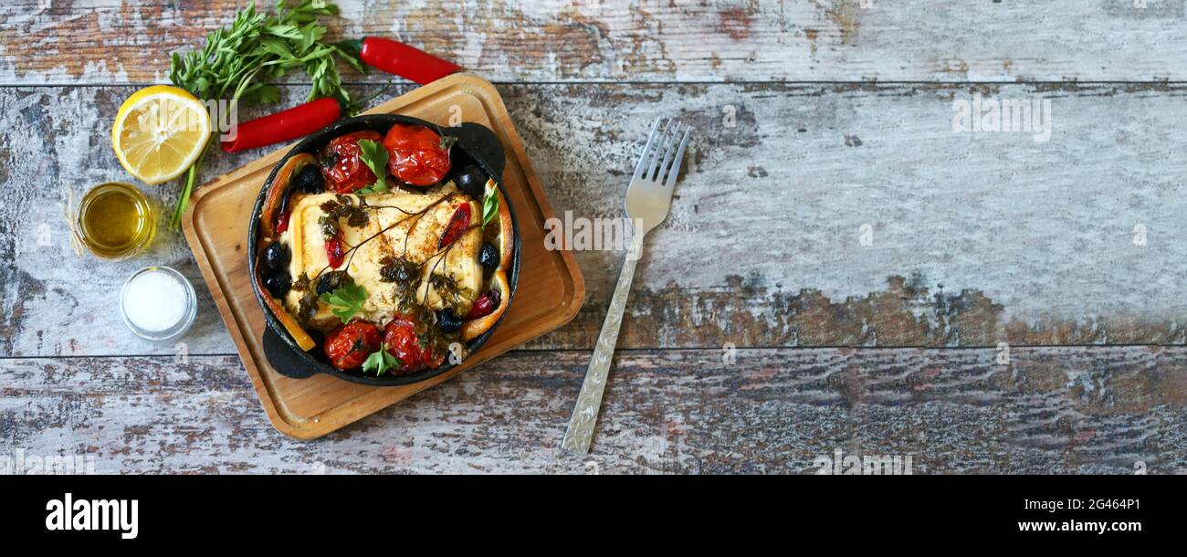 Baked feta cheese. A pan with baked feta, spices and vegetables. Keto