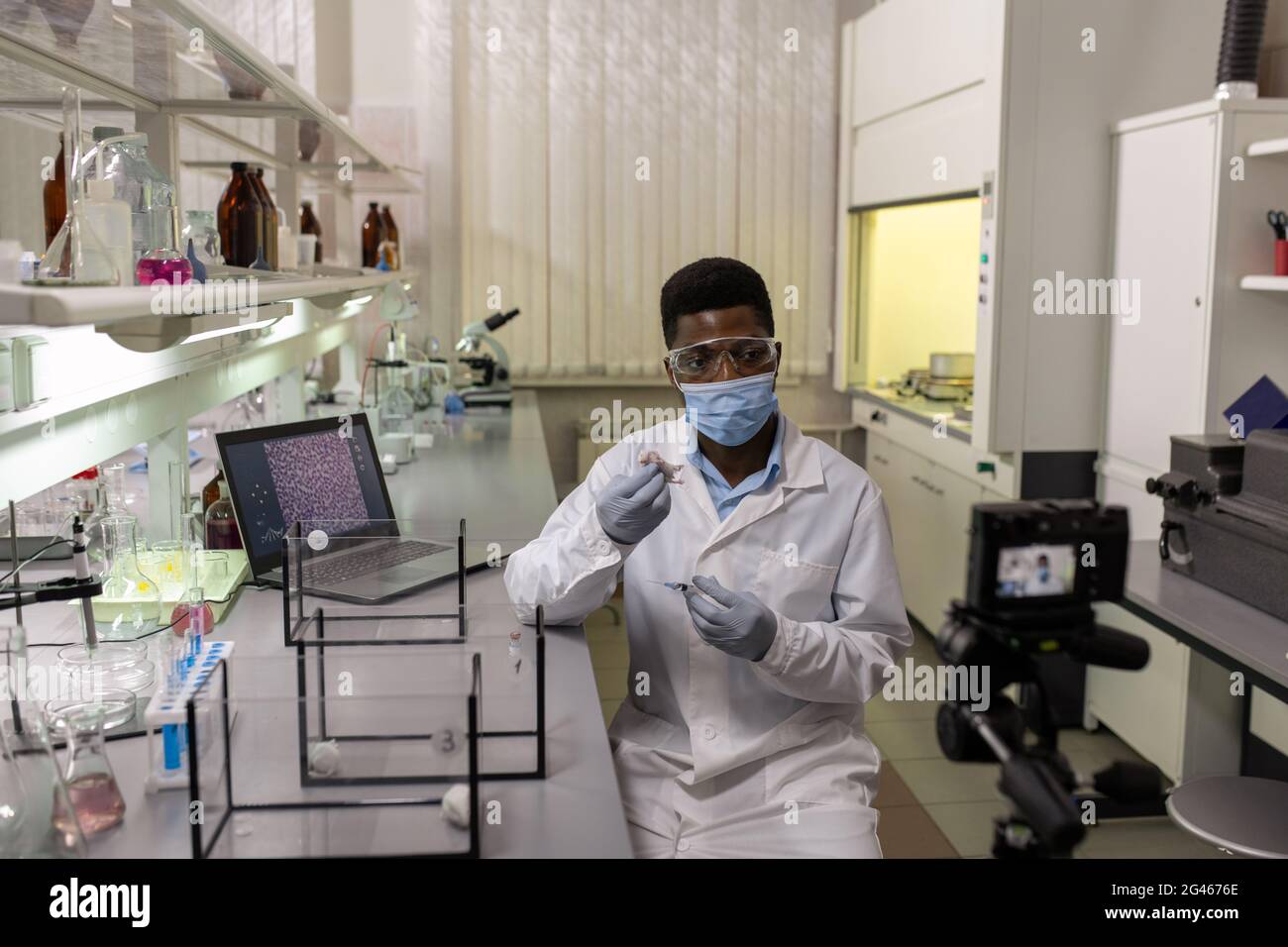 Young scientist in protective mask, gloves and labcoat testing new vaccine in chemical lab Stock Photo
