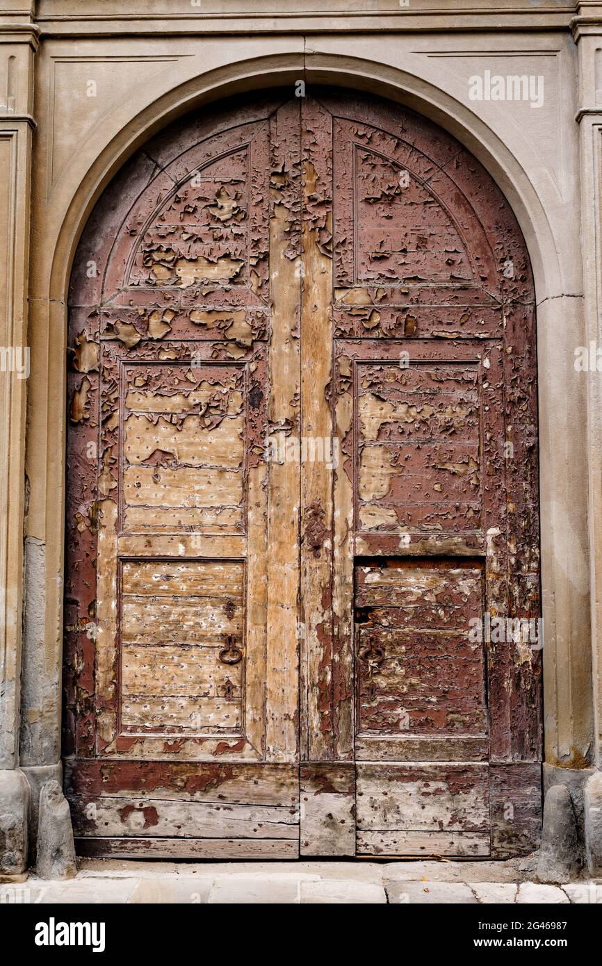 https://c8.alamy.com/comp/2G46987/an-old-wooden-brown-door-with-peeling-paint-in-the-oval-door-between-the-columns-2G46987.jpg