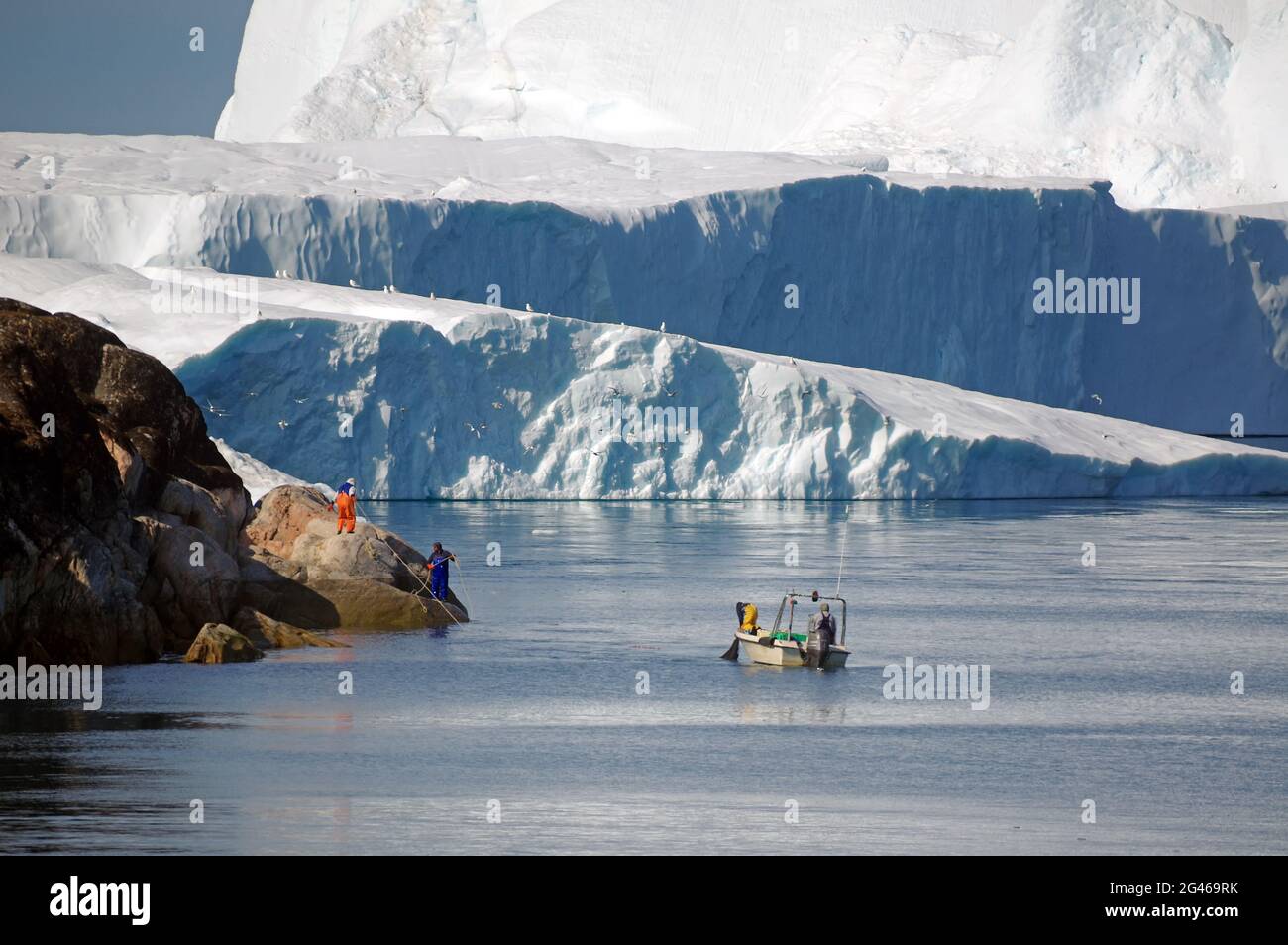 Small fishing vessel in front of icebergs Stock Photo