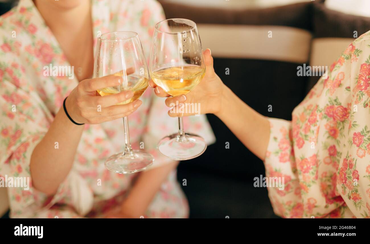 The girls clink glasses of champagne in robes Stock Photo