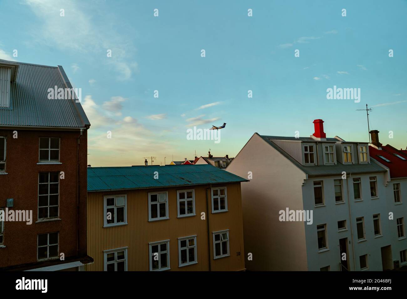 A fokker plane flying low and gliding across the rood of several residential houses in the city center of Reykjavik, Iceland Stock Photo