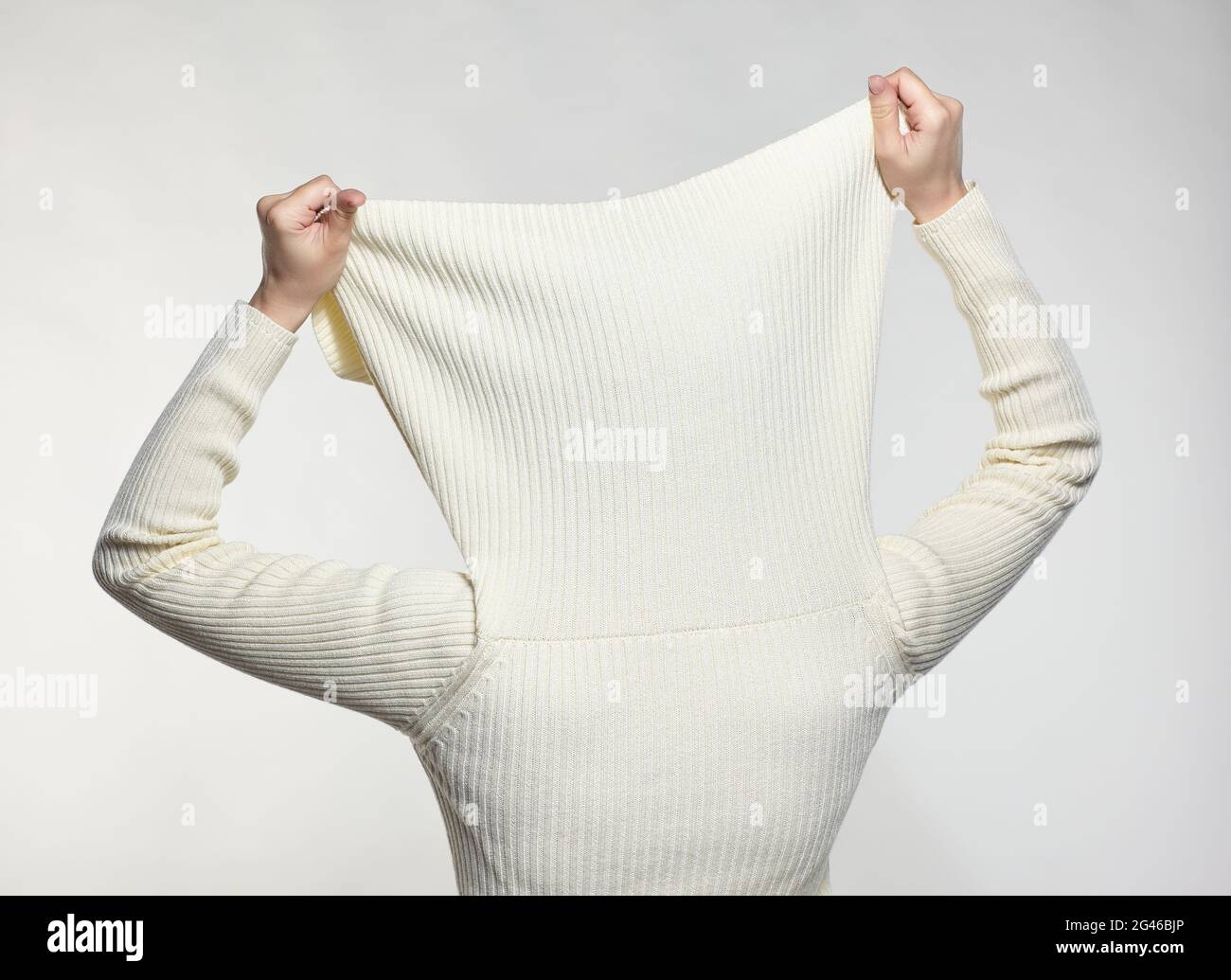 Female with hands on sweater collar hide face Stock Photo - Alamy