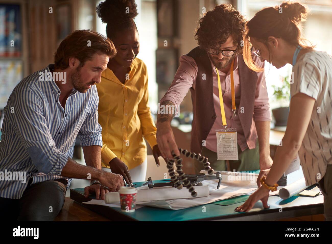 A group of young creative people in a working atmopshere in the office are observing new gadgets they will use in the project. Employees, office, work Stock Photo