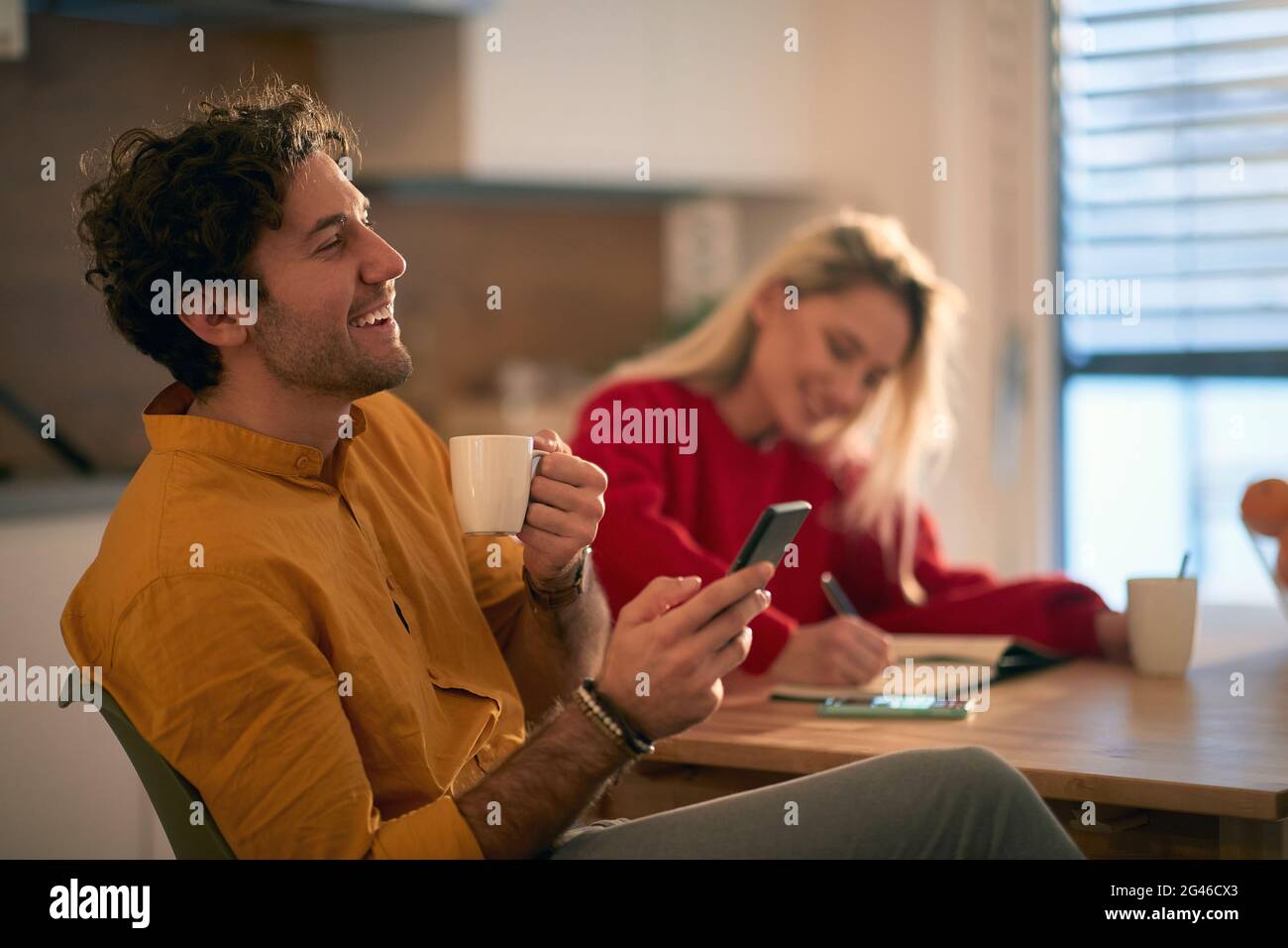 young adult caucasian couple having fun in the morning, drinking coffee, making plans for current day Stock Photo