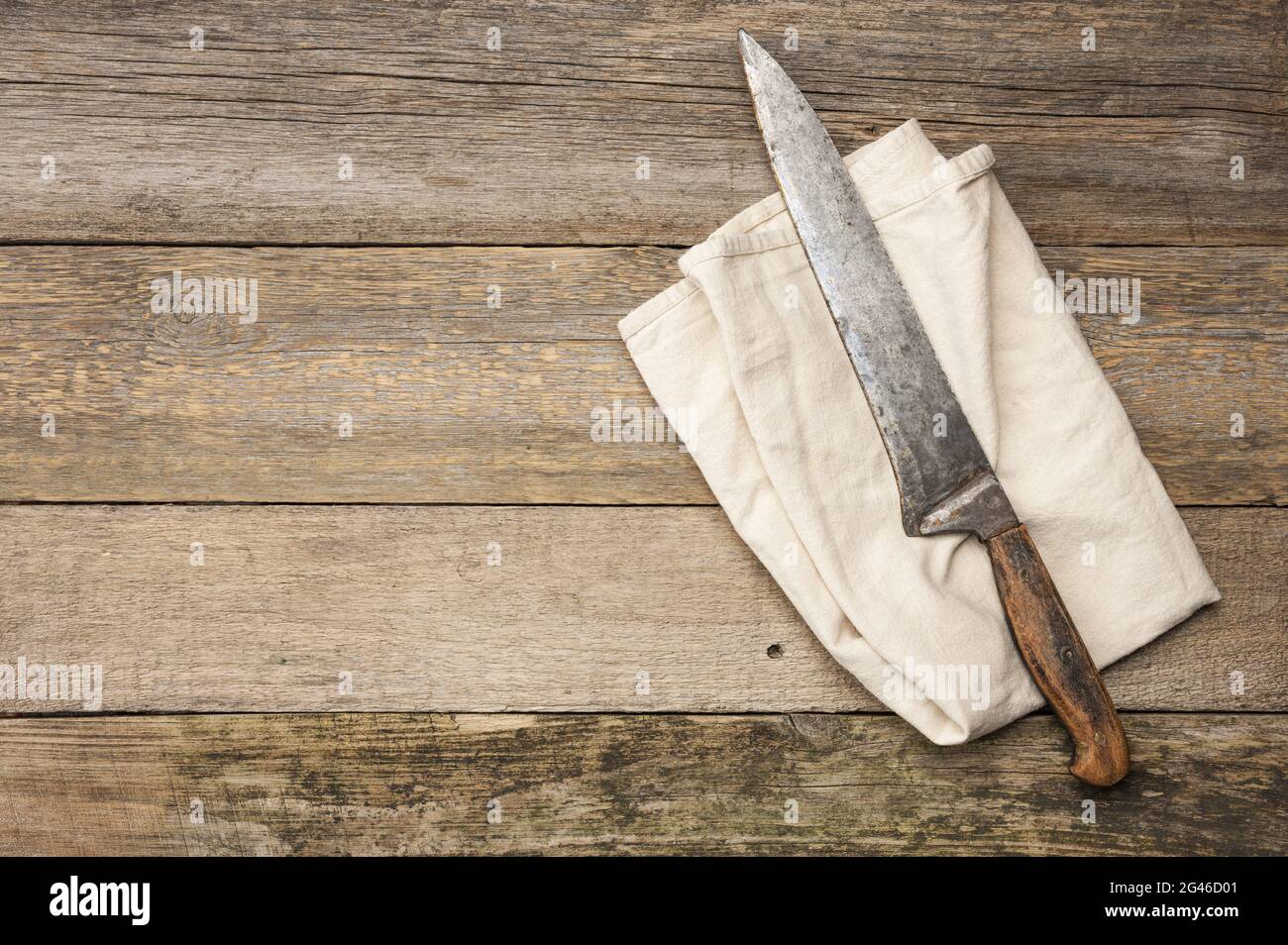 Very old knife and gray linen kitchen towel on a table made of old wooden boards Stock Photo