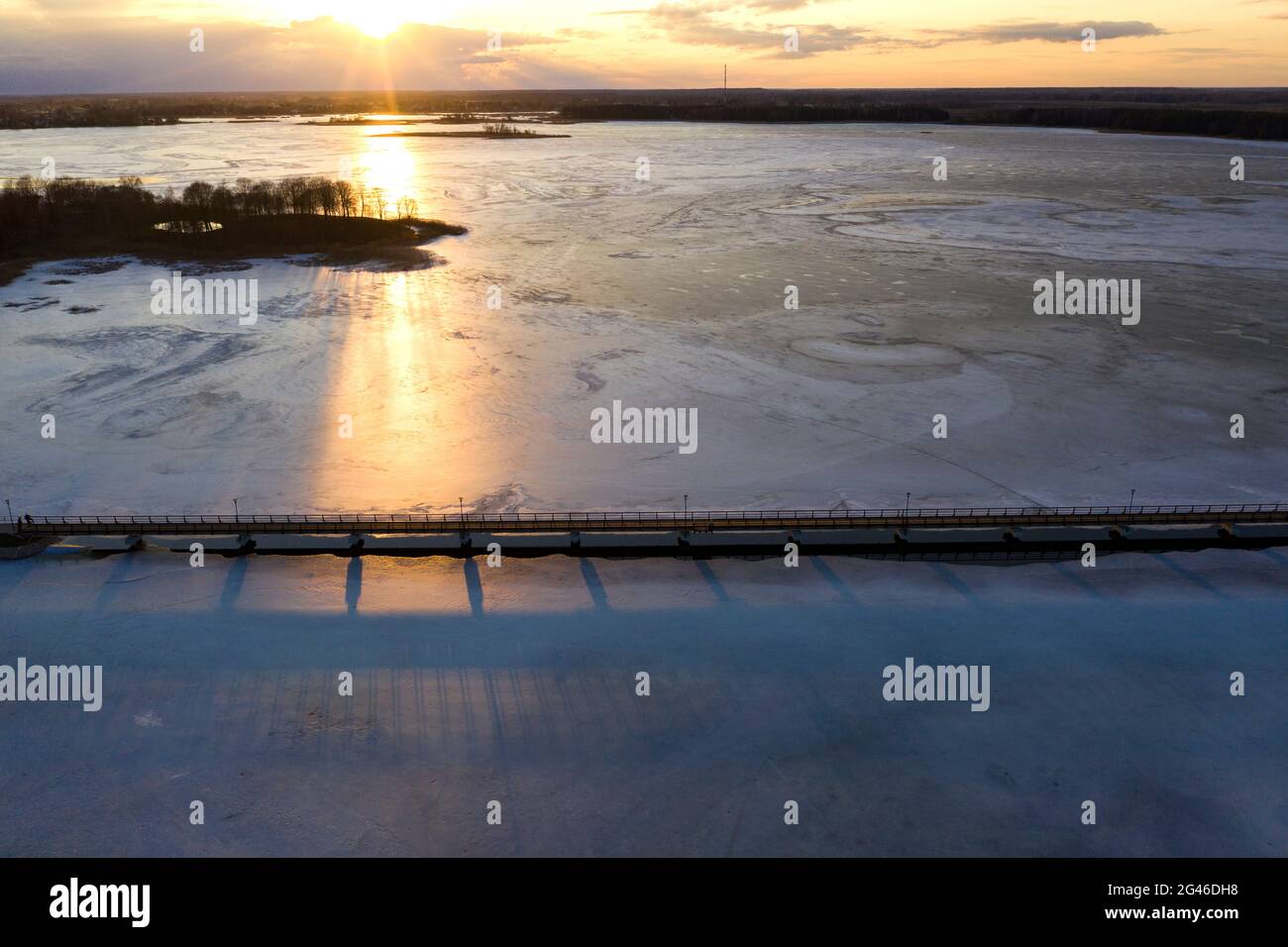 Winter frozen lake with wooden bridge, sunset time, aerial view Stock Photo