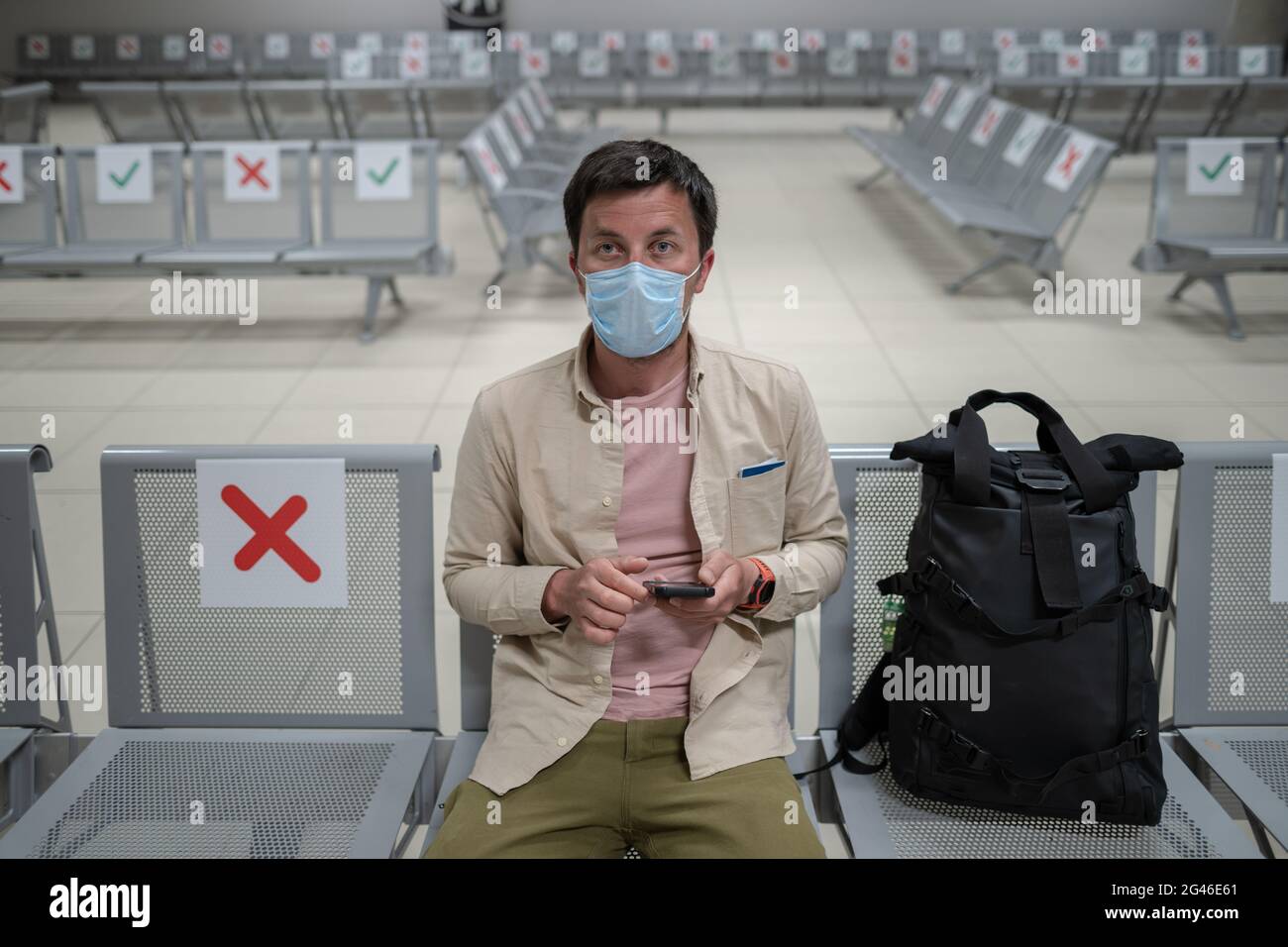 Waiting for flight at empty airport in Cyprus. Man sitting on chair ...