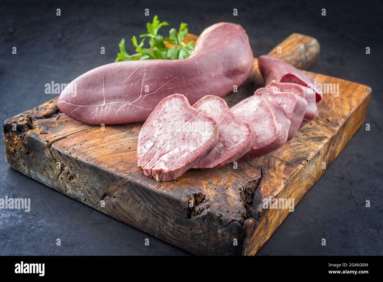 Traditional cooked veal tongue with parsley offered as closeup on a