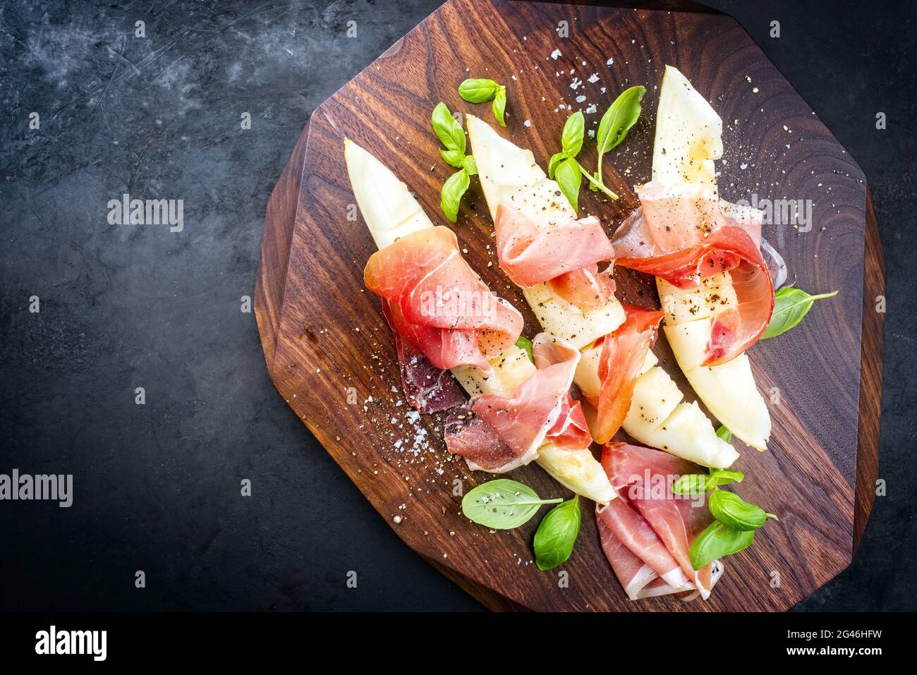 Traditional Italian antipasti with prosciutto di Parma and honeydew melon  slices offered as top view on a wooden design board wi Stock Photo - Alamy