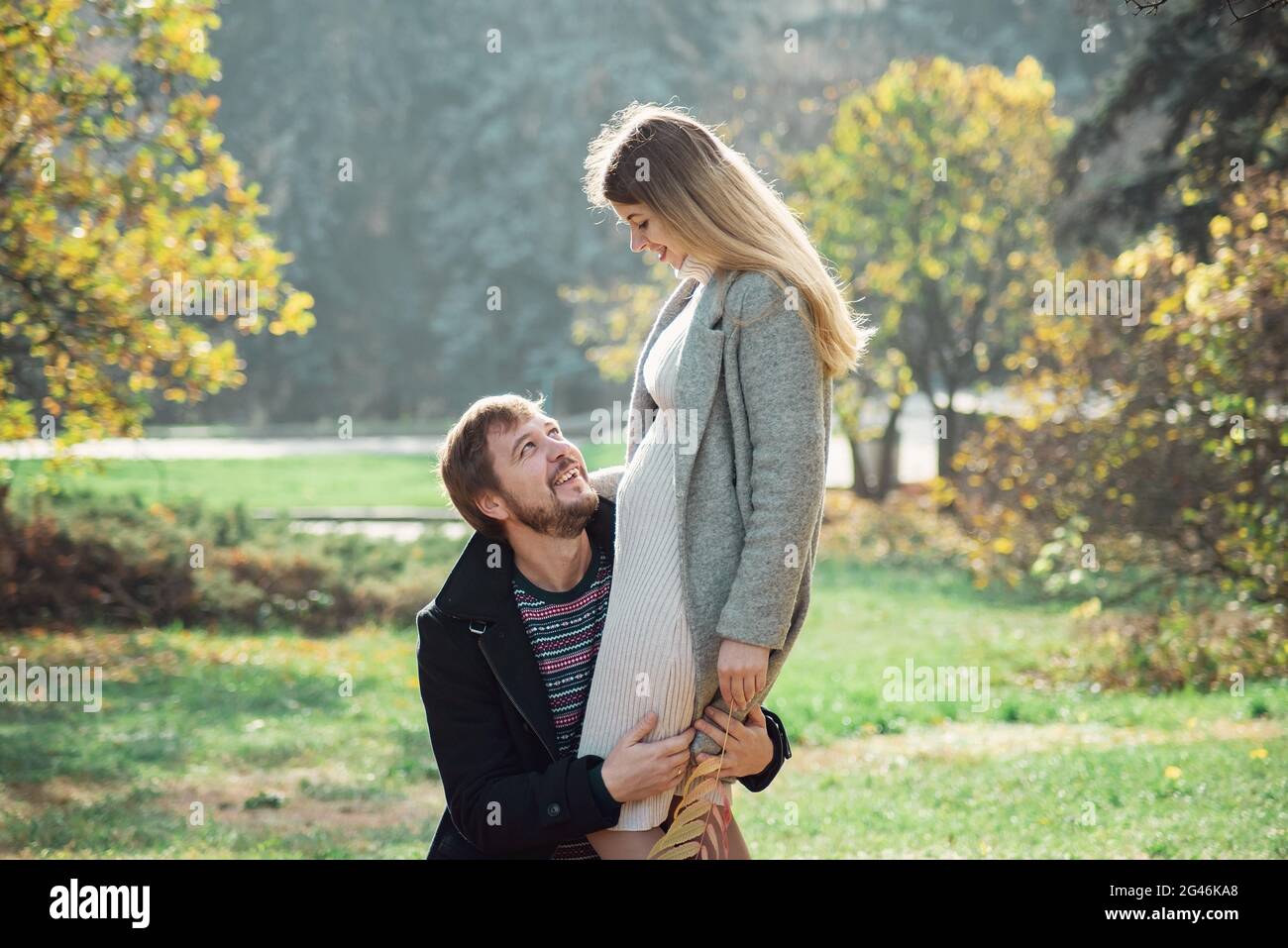 Family together in autumn park. Happy couple Husband and his pregnant wife relaxing in nature. happy married couple expecting baby. Pregnancy, materni Stock Photo