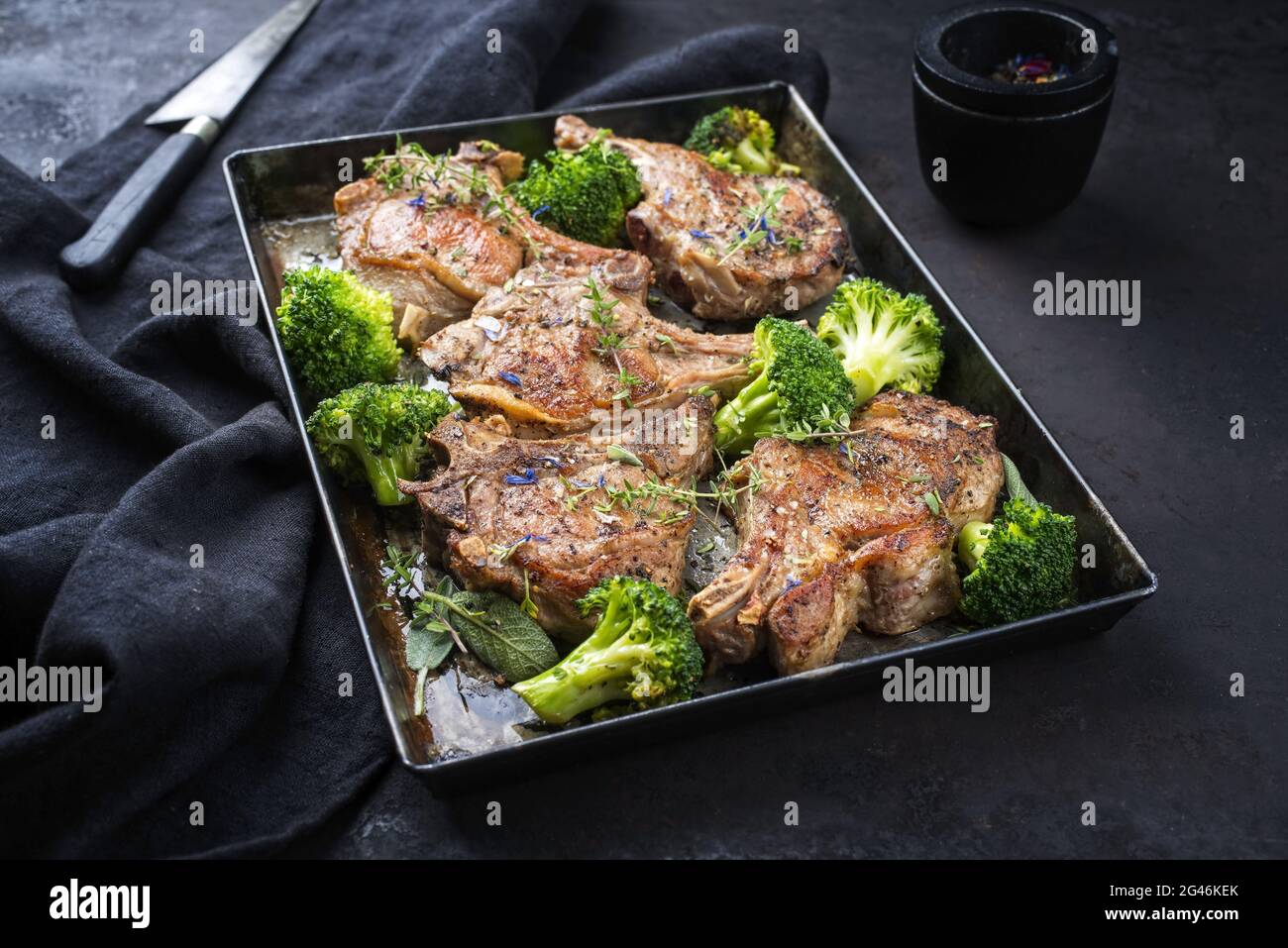 Traditional barbecue dry aged veal chops with baby broccoli served as closeup in a rustic tray