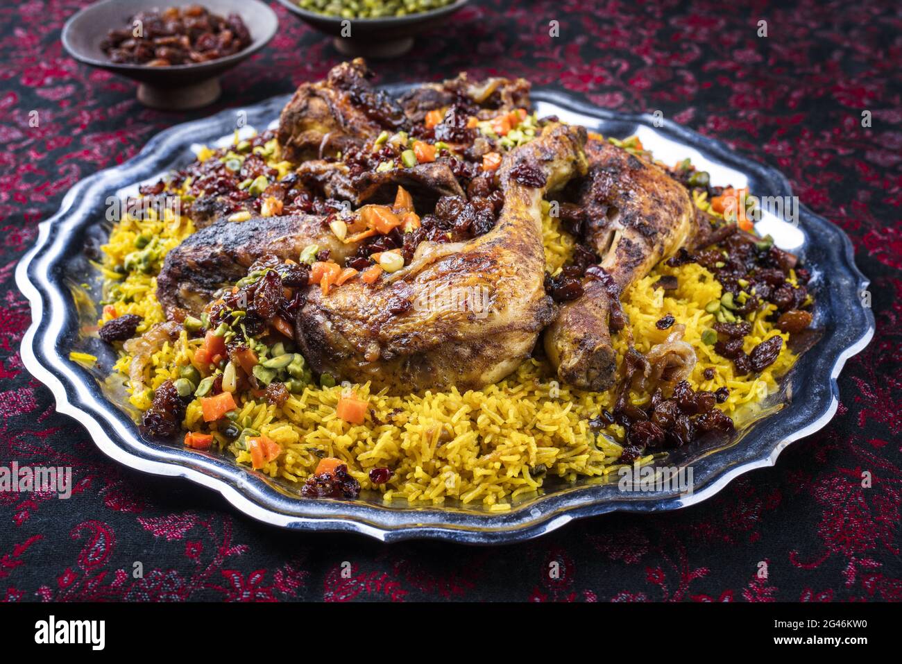 Traditional fried Arabic chicken majboos with chicken leg and jeweled rice served as close-up in a rustic oriental tray Stock Photo