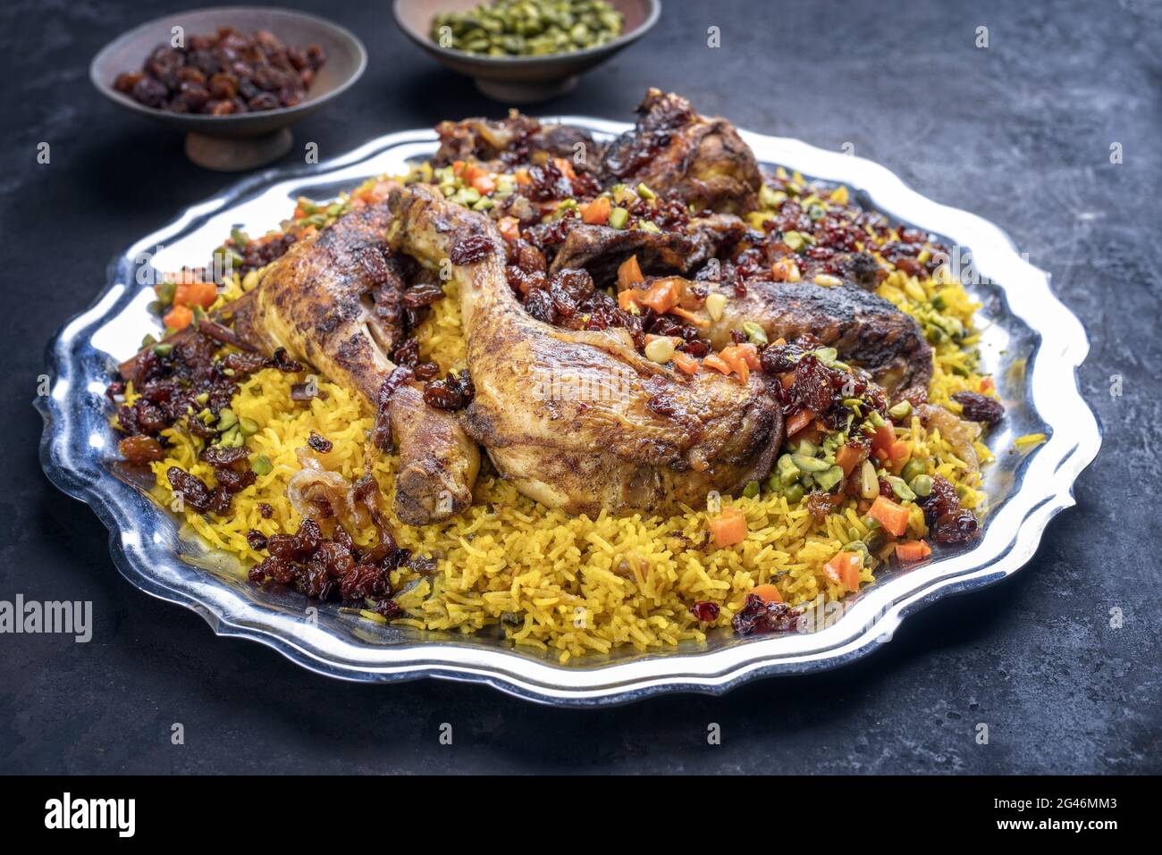 Traditional fried Arabic chicken majboos with chicken leg and jeweled rice served as close-up in a rustic oriental tray Stock Photo