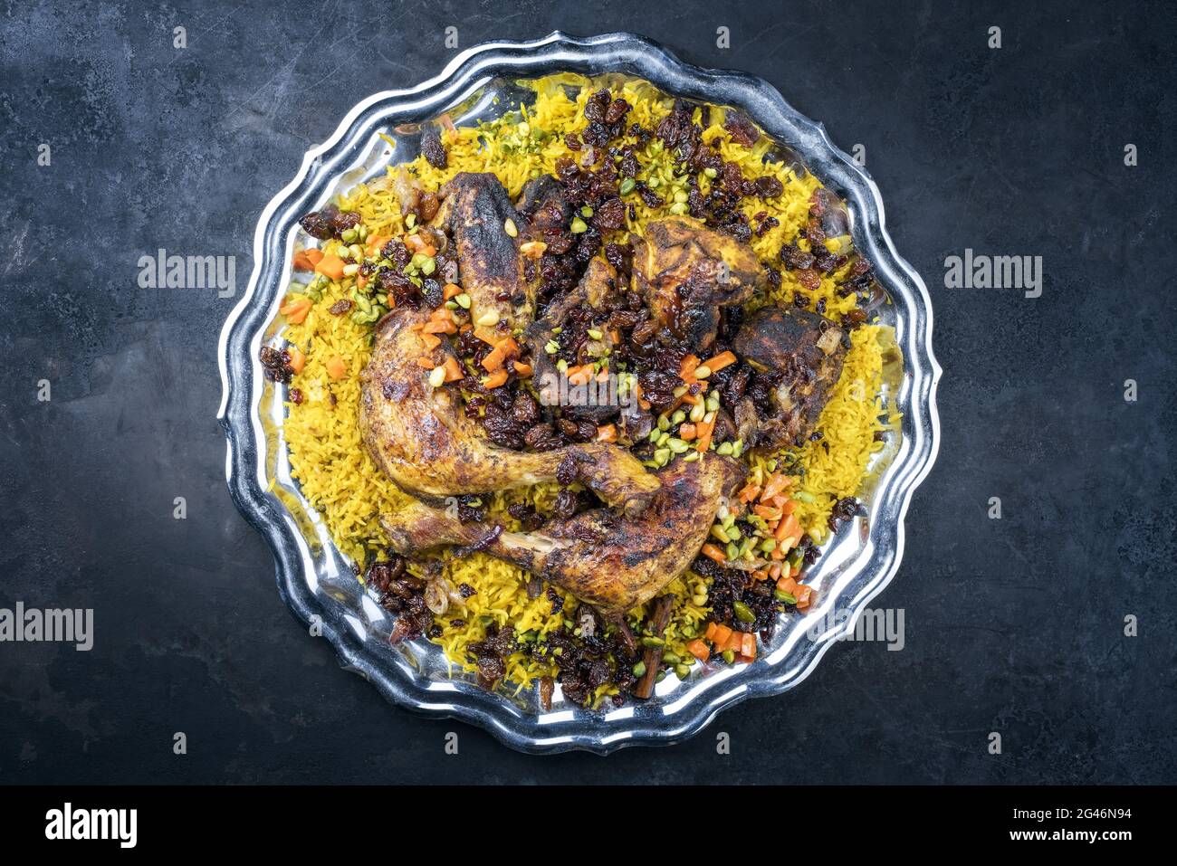 Traditional fried Arabic chicken majboos with chicken leg and jeweled rice served as top view in a rustic oriental tray Stock Photo