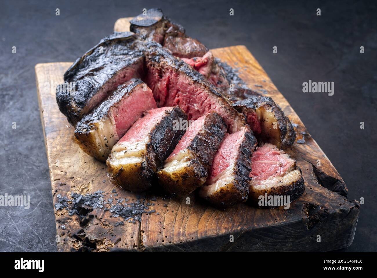 Traditional barbecue dry aged wagyu t-bone beef steak bistecca alla Fiorentina sliced and served with black salt as close-up on Stock Photo