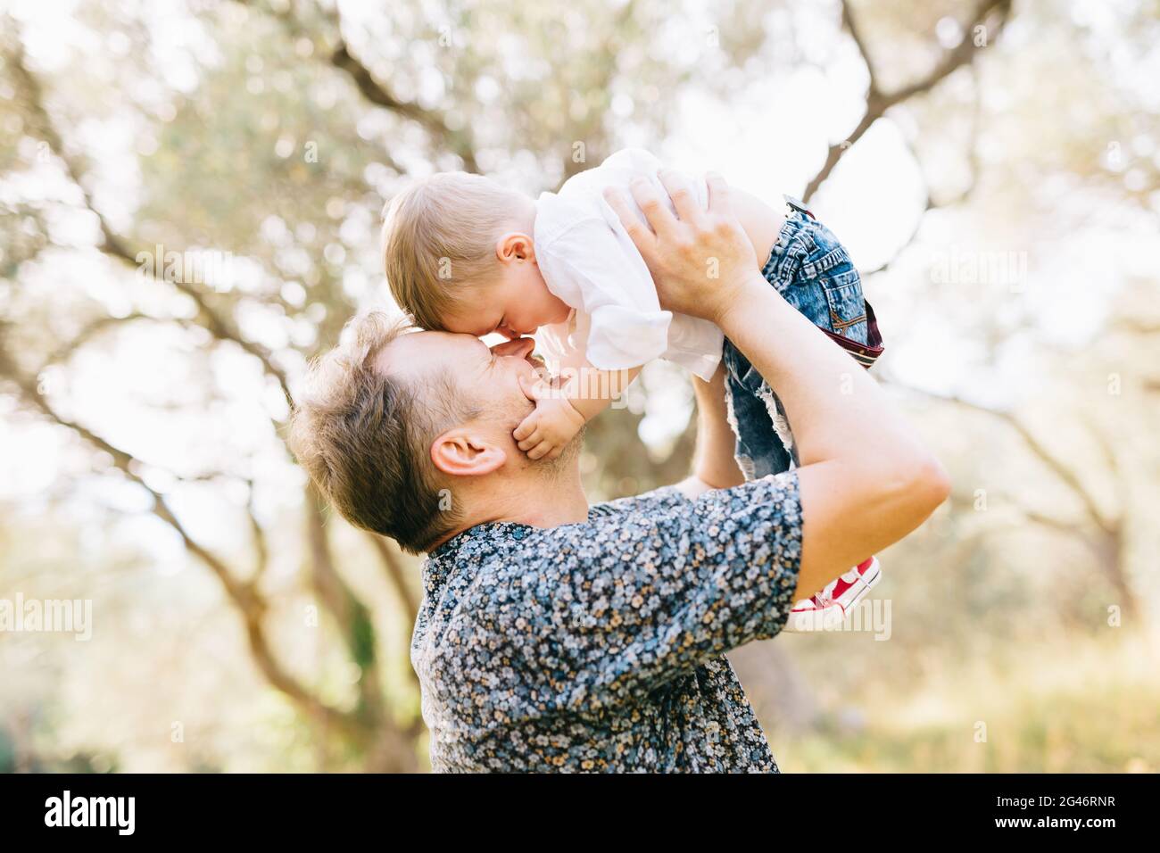 The father holds his son above him, they touching their noses, the son holds the father by the cheek Stock Photo