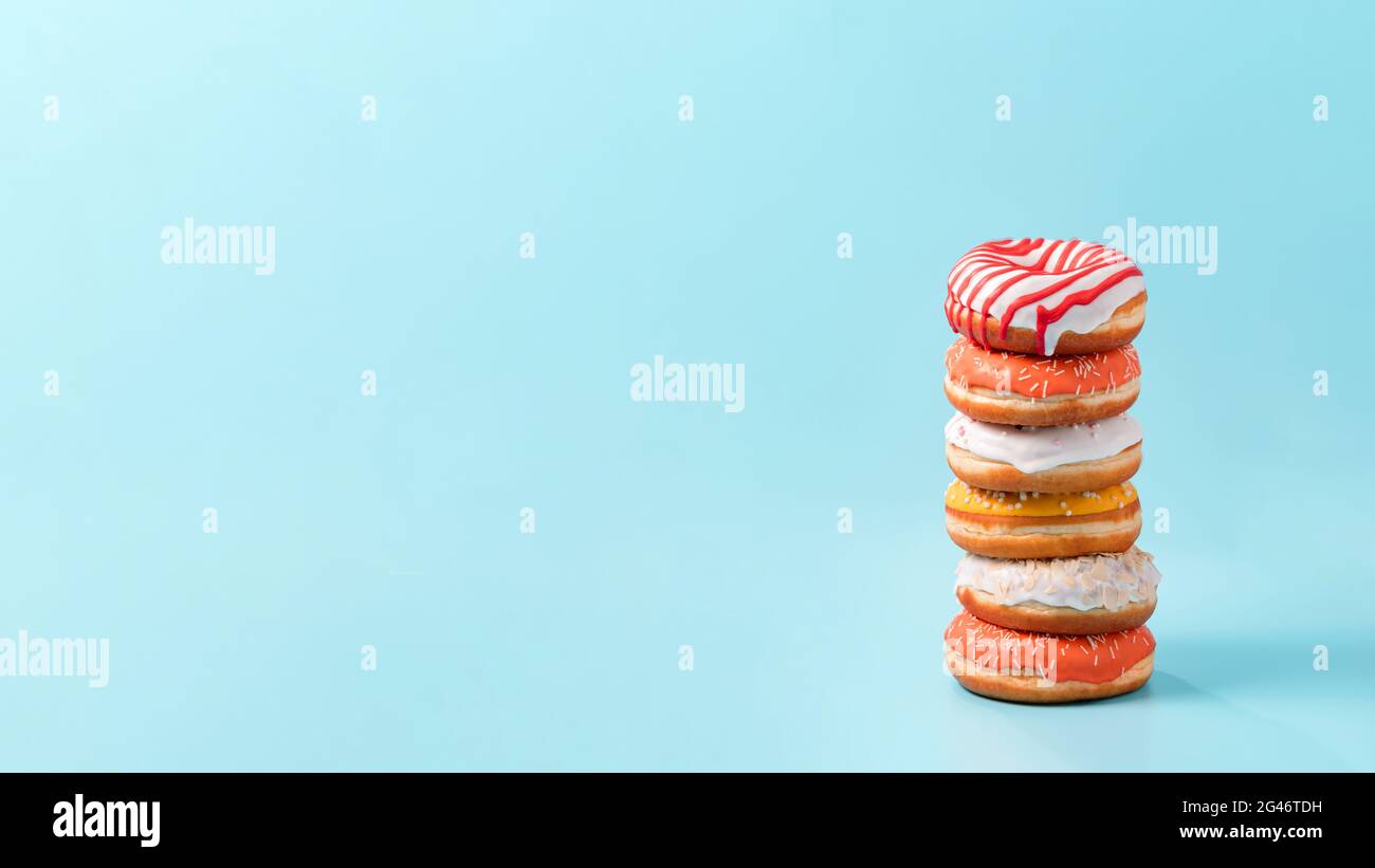 Stack of donuts on blue background with copy space Stock Photo