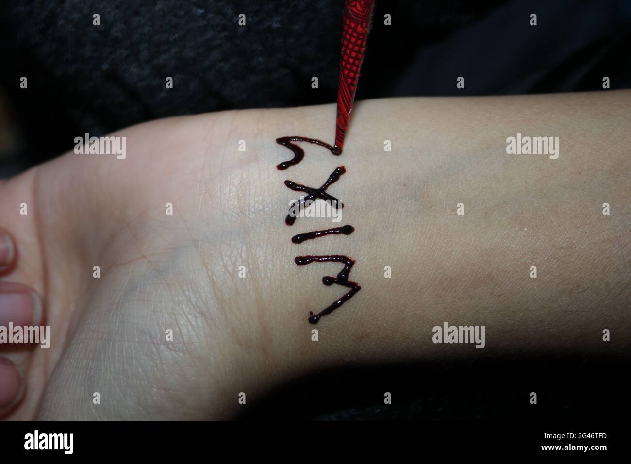 Drawing process of henna menhdi text on a girl's hand. Stock Photo