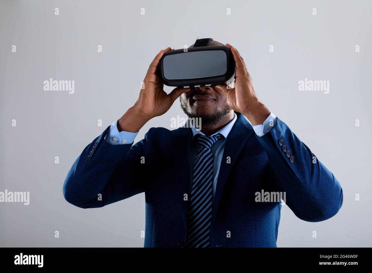 African american businessman wearing vr headset smiling against grey background Stock Photo