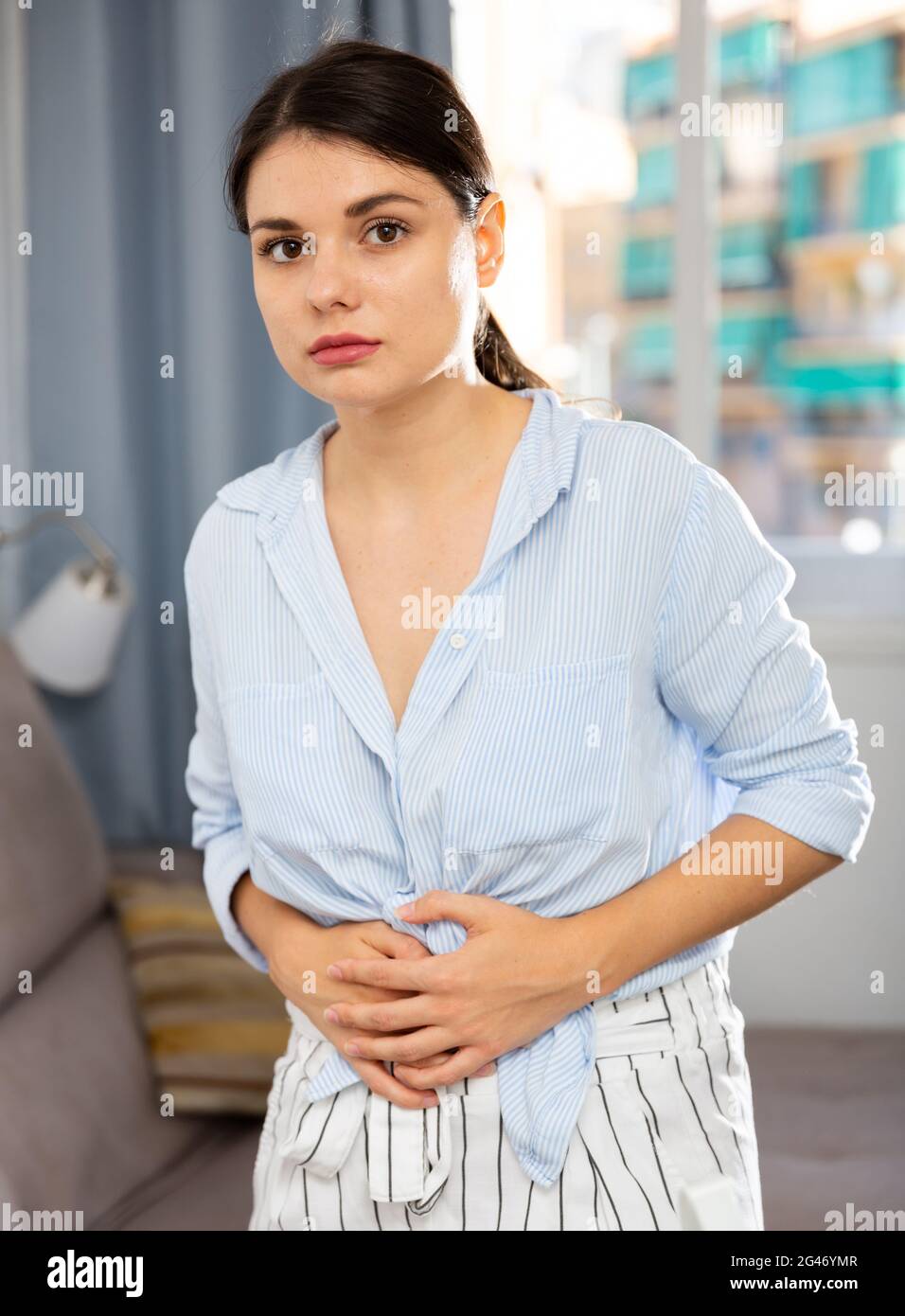 Young woman experiencing pain in the stomach Stock Photo