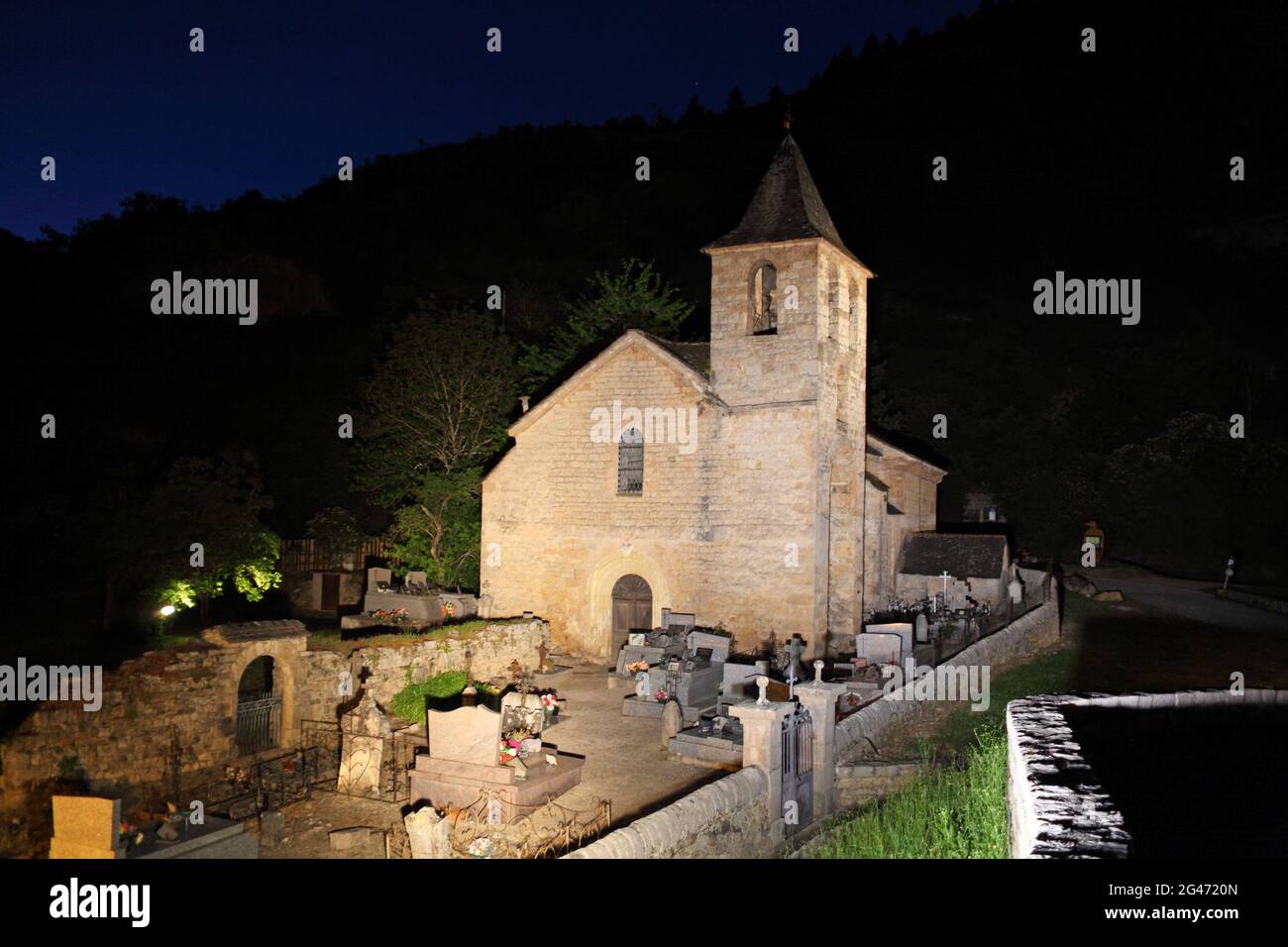 Church, part of former monastery floodlit at night, in the spectacular remote village of St Chely du Tarn, Lozere, France. Gorges of the Tarn and Jonte, and the Grands Causses are a top Occitania site soon to be listed Grand Site of France Stock Photo