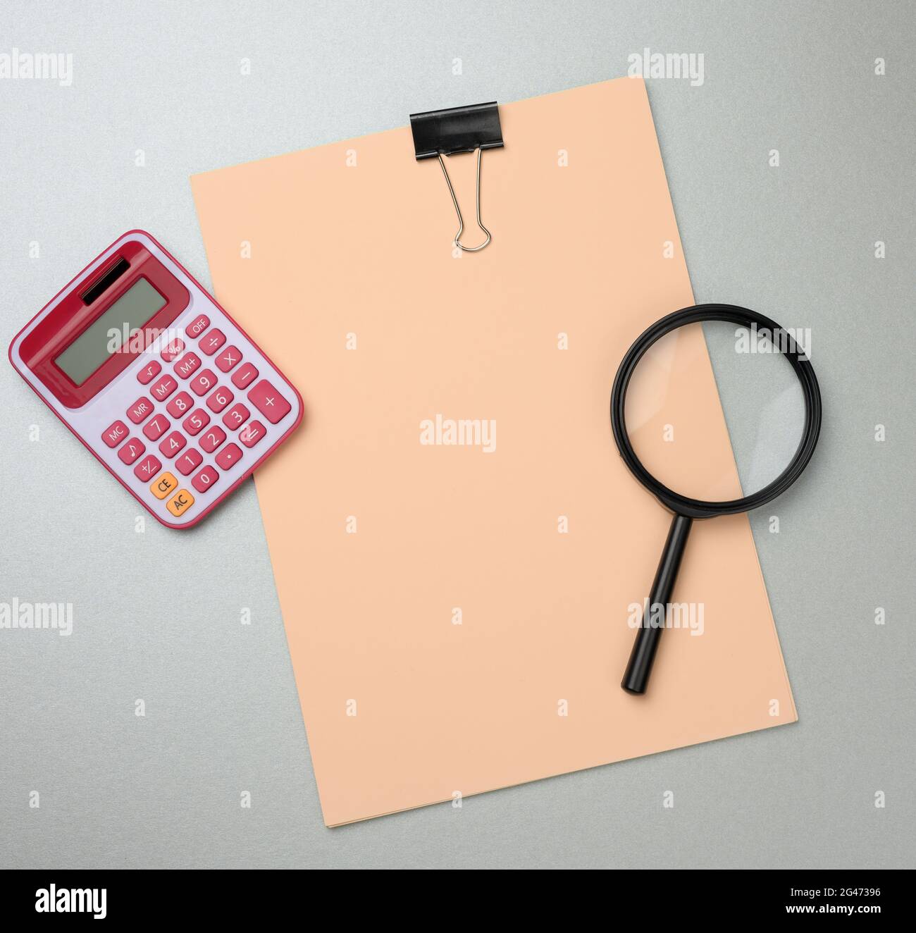 Pink calculator, folder with blank  sheets and black magnifier on a gray background Stock Photo