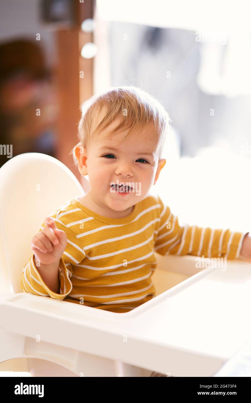 Laughing cute baby sitting on the highchair. Close-up Stock Photo