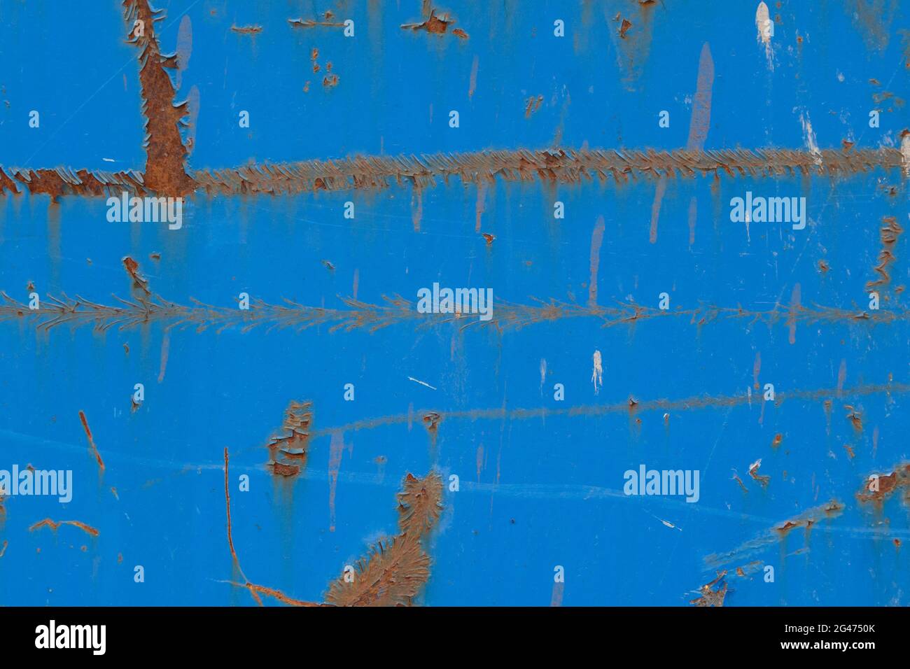 Close-up of a weathered sheet metal plate painted in blue. Paint is partly peeled off revealing rusty metal. Full frame abstract background. Stock Photo