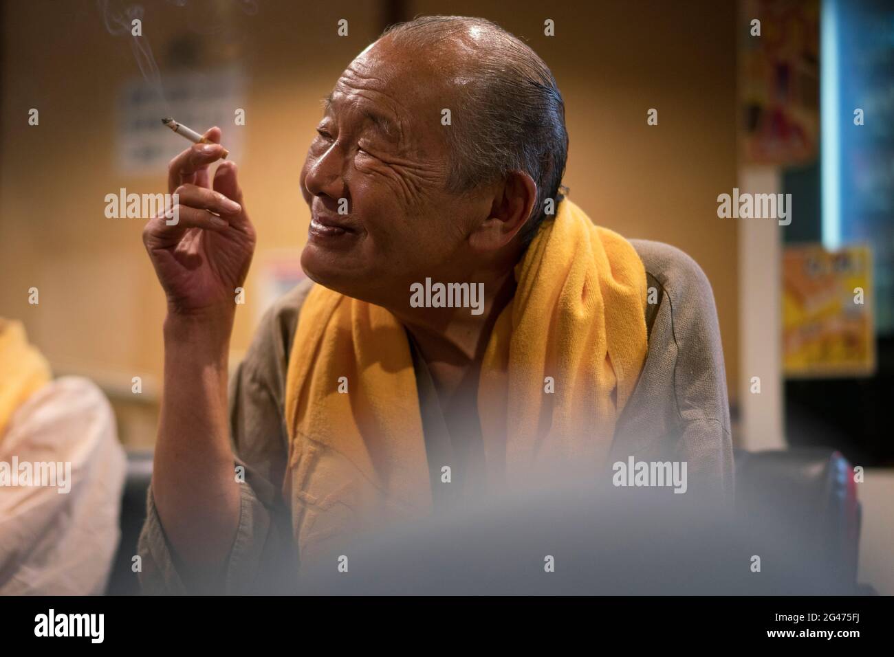 Portrait of an old Japanese man smoking indoors in Tokyo Stock Photo