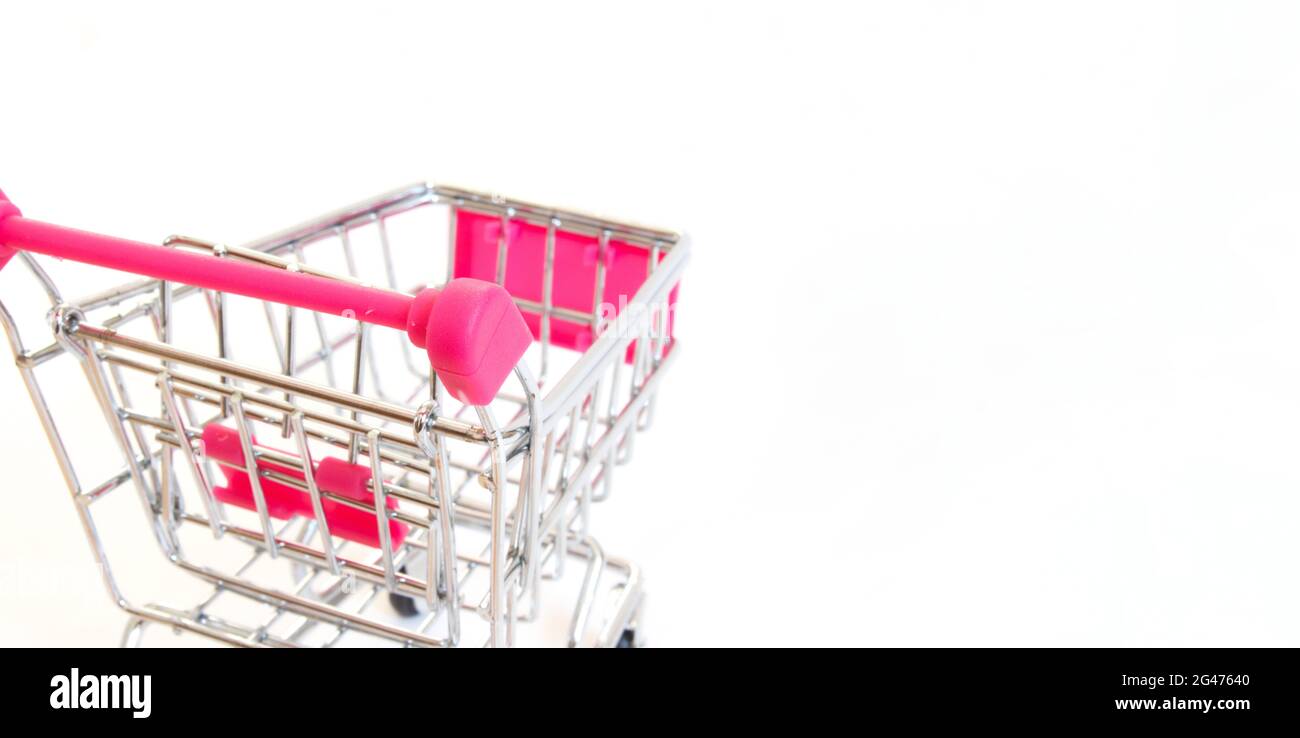 Mini shopping cart, closeup pink empty shopping cart isolated on white background with copy space. Stock Photo