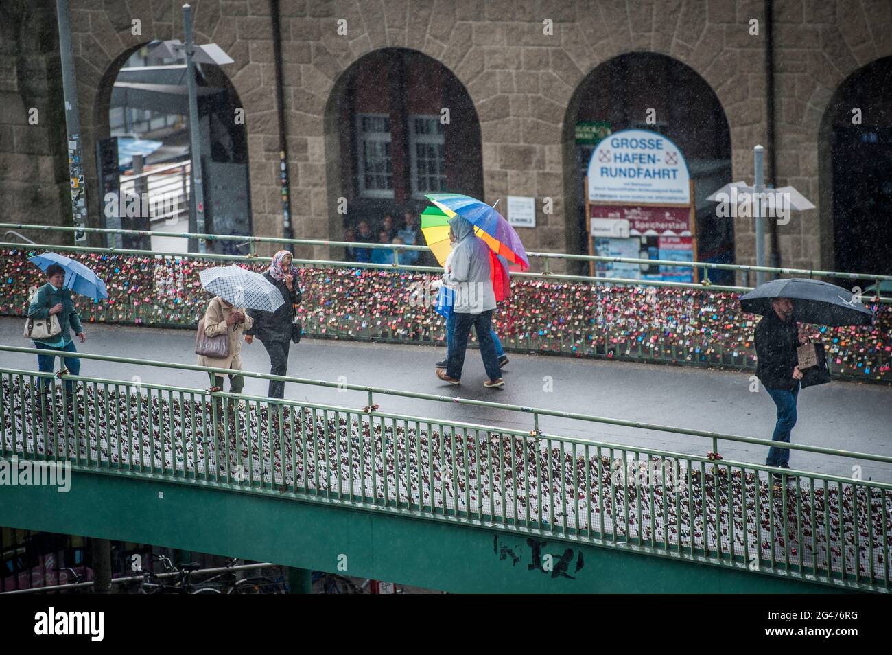 Regen in Hamburg. Fußgängerbrücke mit Passanten und Regenschirmen an den Landungsbrücken. Stock Photo