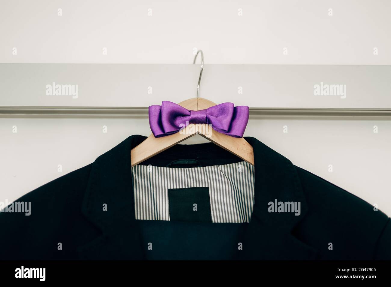Jacket with striped lining and purple bow tie on a hanger. Stock Photo