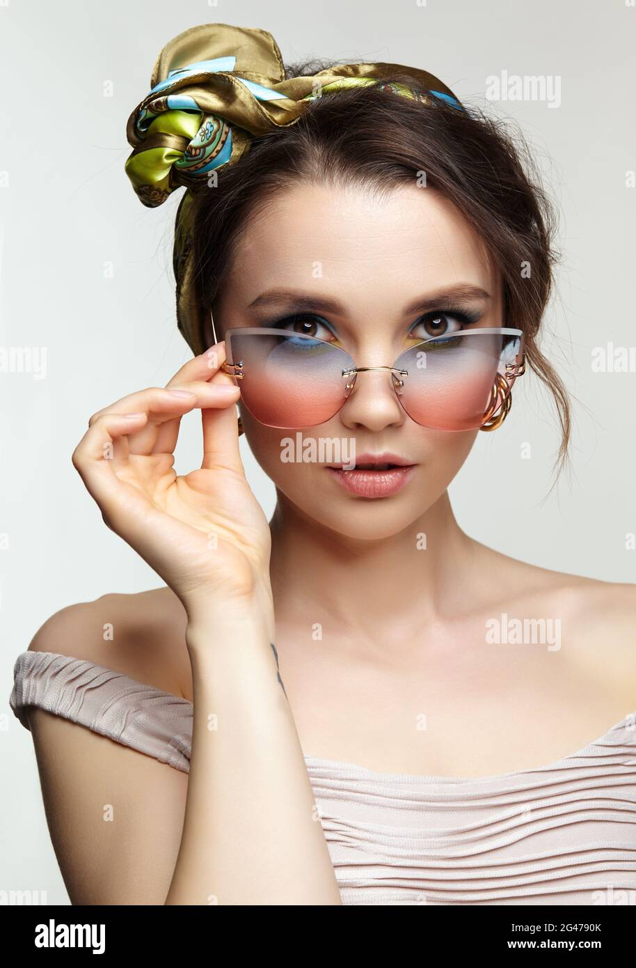 Female in headscarf is looking at the camera through sunglasses. Stock Photo