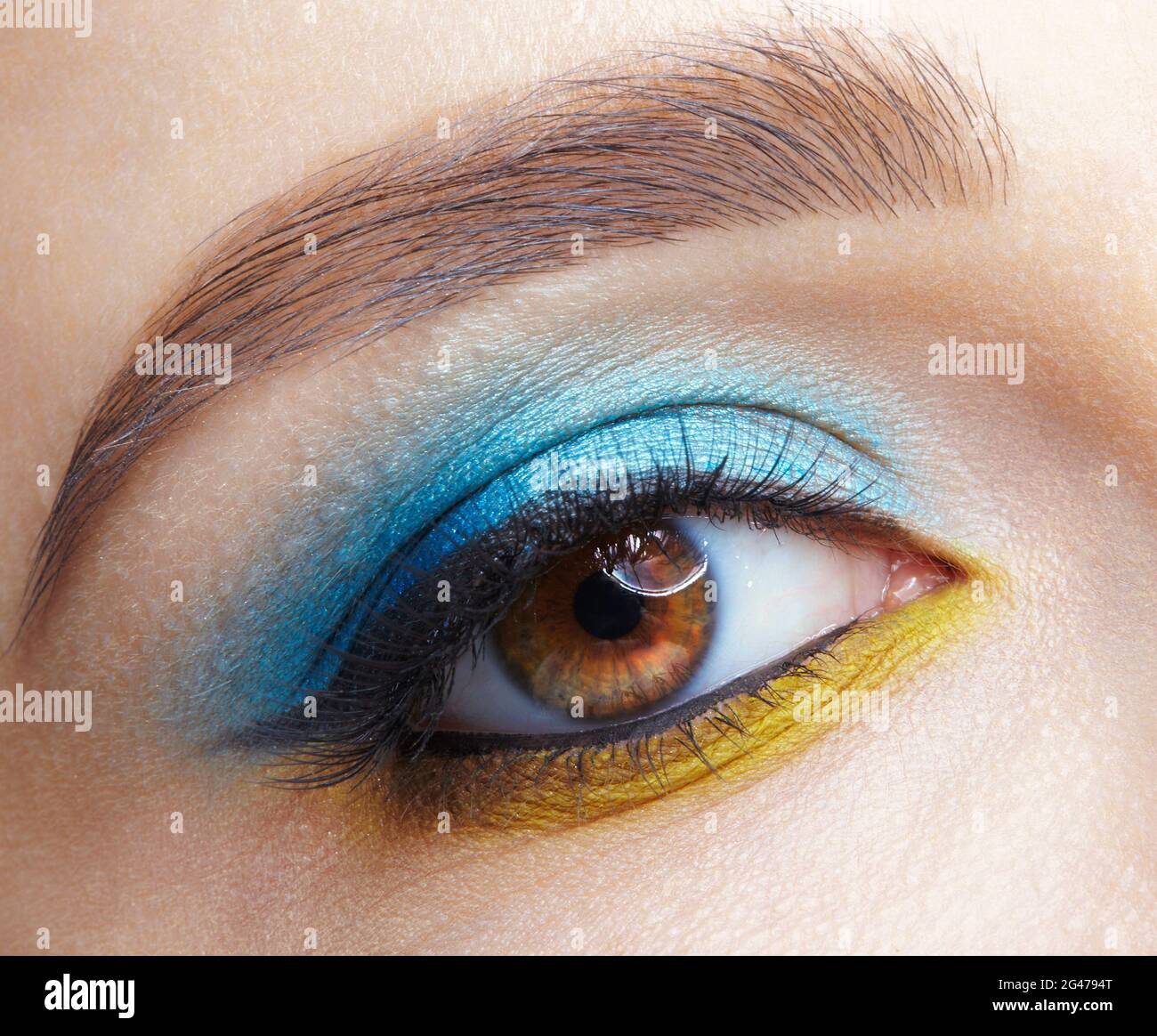 Human female eye with blue smoky eyes shadows and yellow liner. Stock Photo