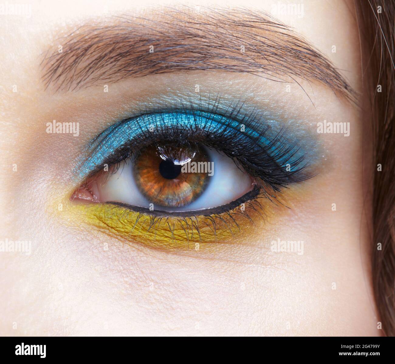 Human female eye with blue smoky eyes shadows and yellow liner. Stock Photo