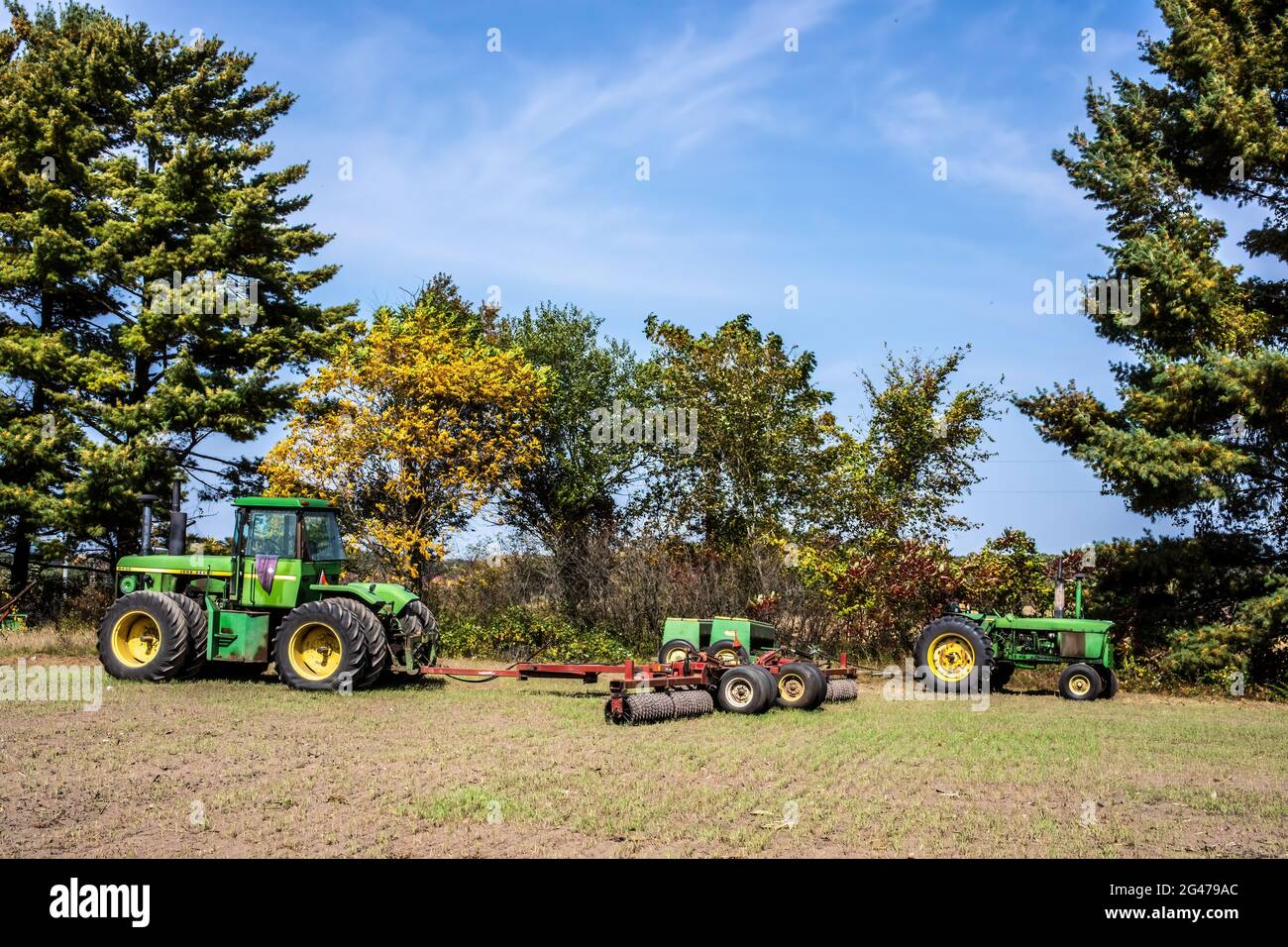 8430 John Deere 8 Wheeler  Tractor with 32' Roller and a 4320 John Deere Tractor with an 8300 Grain Drill in a farm field. Stock Photo